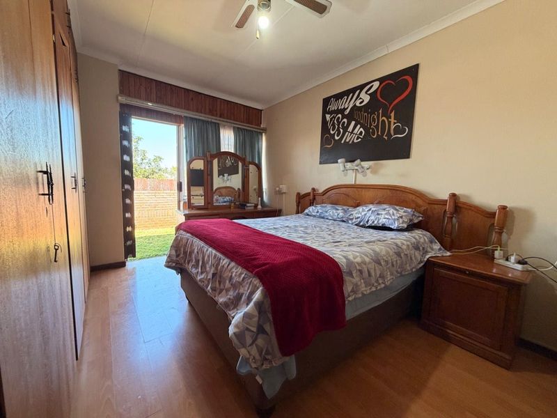 Spacious bedroom featuring built-in cupboards, laminate flooring, and a sliding door providing direct access to the rear garden area.