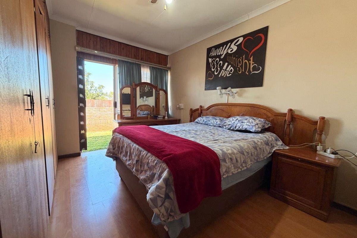 Spacious bedroom featuring built-in cupboards, laminate flooring, and a sliding door providing direct access to the rear garden area.