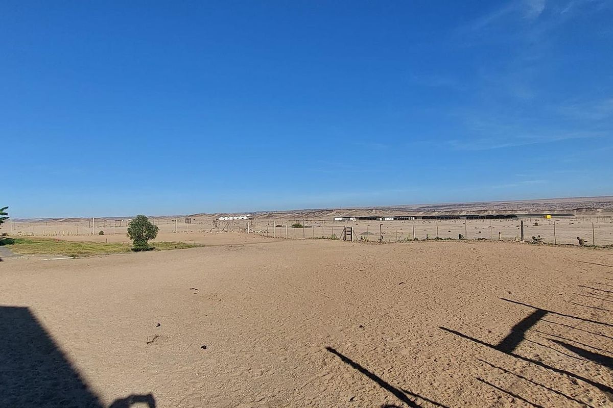 Expansive view of the surrounding arid landscape and open land, featuring perimeter wire fencing and a clear horizon line.