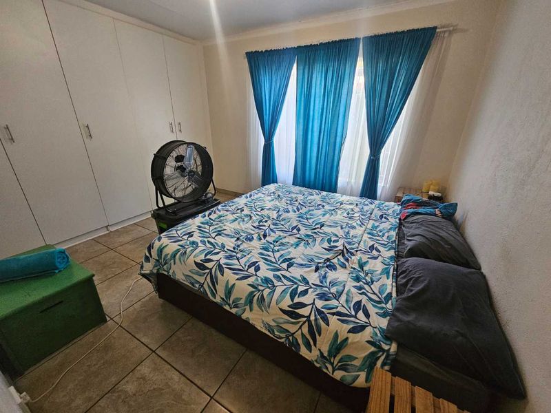 A bedroom featuring built-in cupboards and tiled flooring, providing a functional space with neutral finishes.