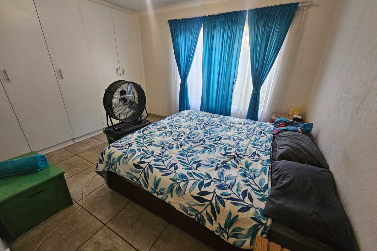 A bedroom featuring built-in cupboards and tiled flooring, providing a functional space with neutral finishes.