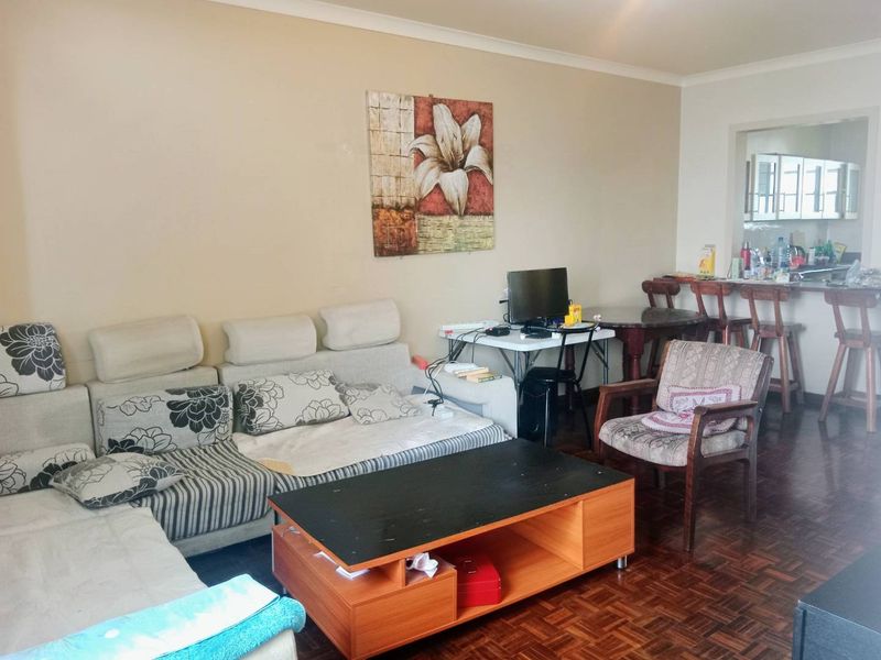 Open plan living area featuring parquet flooring and a breakfast bar connecting to the kitchen space.