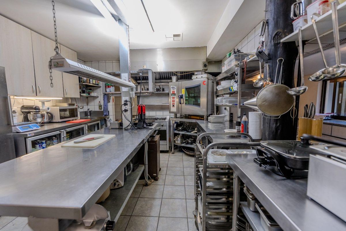 A functional commercial-grade kitchen featuring stainless steel work surfaces, built-in cabinetry, and professional cooking equipment, suitable for high-volume food preparation.