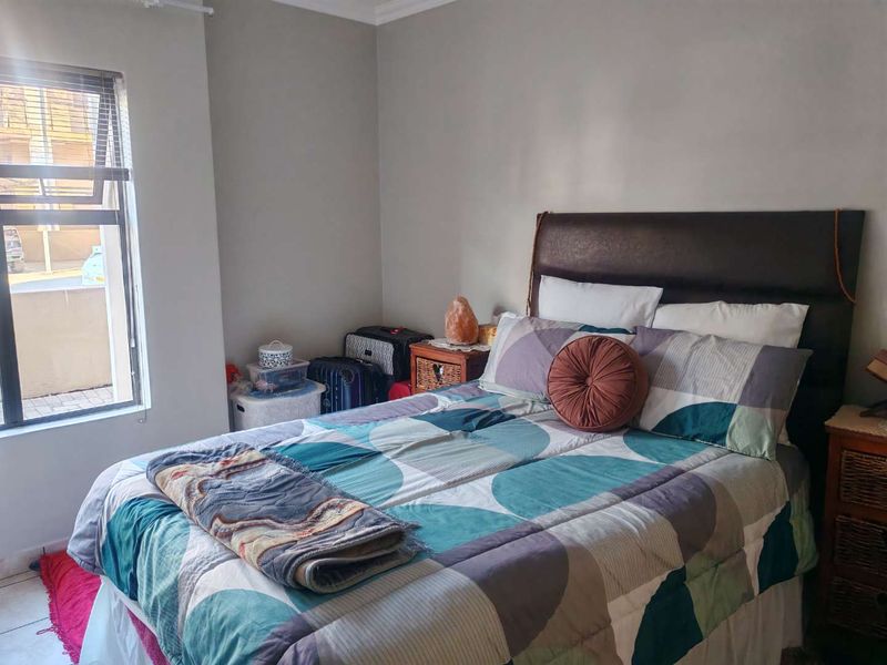 A bedroom featuring neutral wall tones and an aluminium window frame, providing a functional space with natural light.