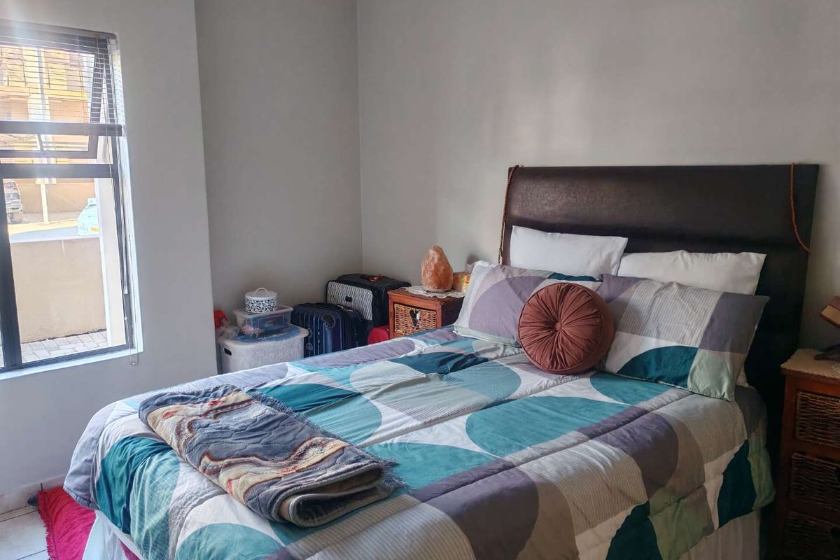 A bedroom featuring neutral wall tones and an aluminium window frame, providing a functional space with natural light.