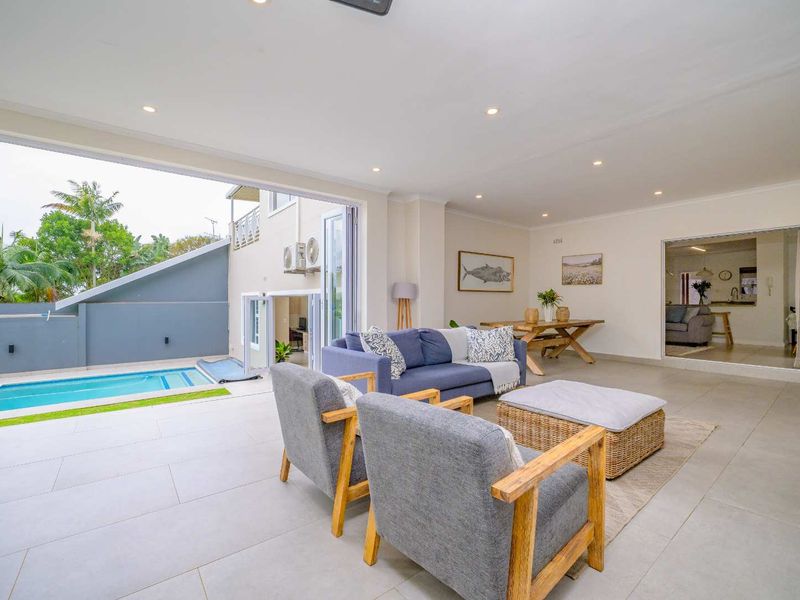 Spacious open-plan living area featuring large bi-fold doors that open onto a private swimming pool and outdoor patio space.