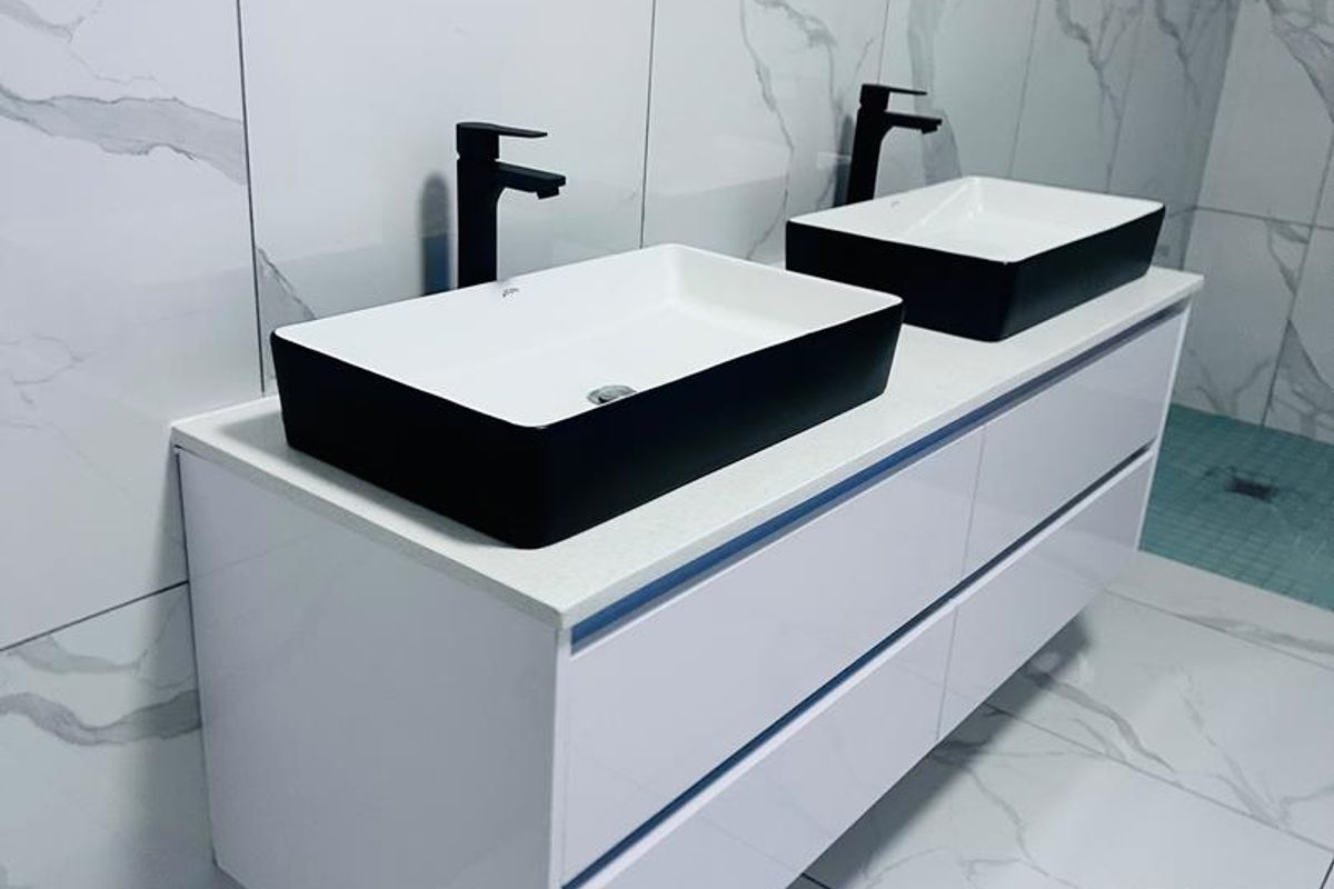 Modern bathroom featuring a wall-mounted double vanity with dual vessel sinks, matte black faucets, and floor-to-ceiling marble-look porcelain wall and floor tiles.