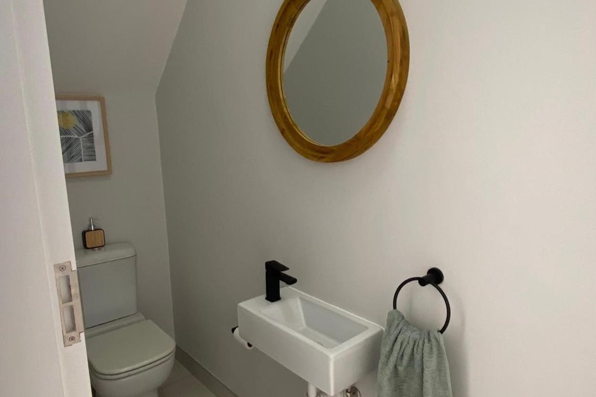 A compact guest bathroom featuring a wall-mounted basin with a modern black mixer tap and a standard toilet.