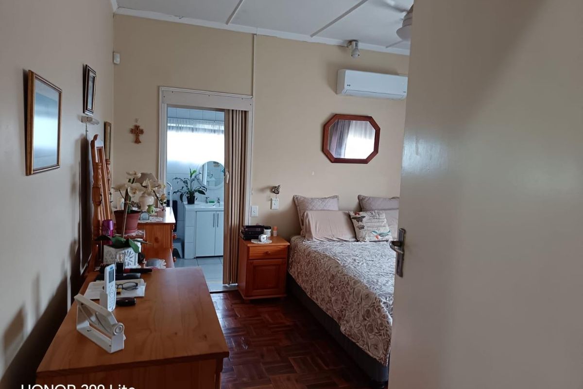 A bedroom featuring parquet flooring, a wall-mounted air conditioning unit, and direct access to an en-suite bathroom.