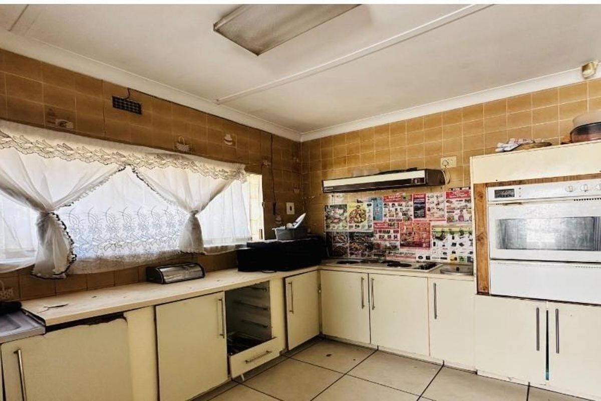 A dated kitchen featuring built-in cabinetry, an integrated oven, hob, extractor fan, and tiled splashbacks, offering significant potential for a modern renovation.