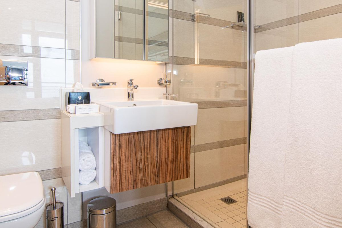Modern bathroom featuring a wall-mounted vanity with integrated basin, a glass-enclosed shower, and a concealed cistern toilet with tiled wall finishes.