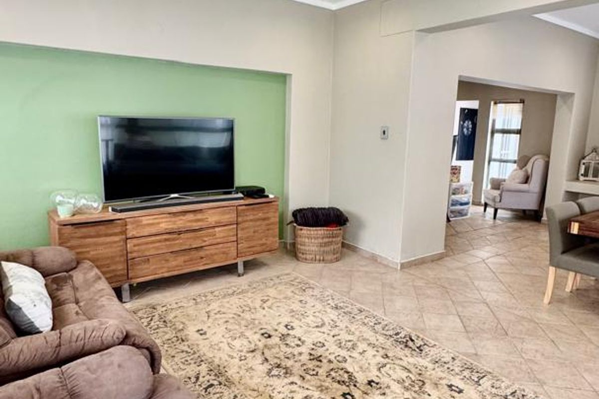A spacious living area featuring tiled flooring, a recessed wall feature, and a white tongue-and-groove ceiling with integrated downlights.