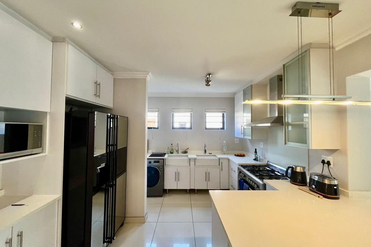 Modern kitchen featuring white cabinetry, stone countertops, a gas hob with extractor, and a double farmhouse sink with tiled flooring.