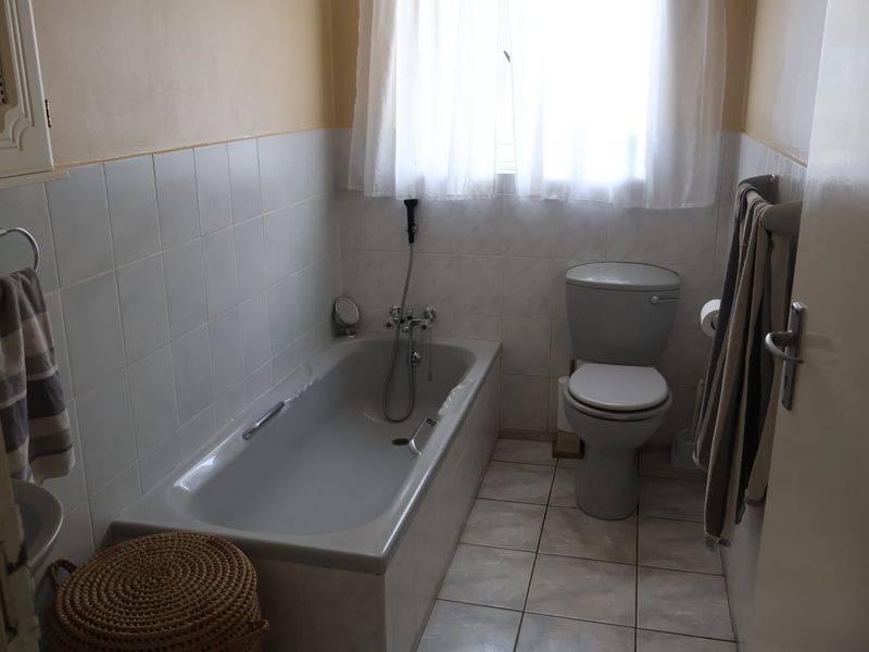 A functional bathroom featuring a bathtub, toilet, and tiled finishes, offering a clean and practical space with potential for modern updates.