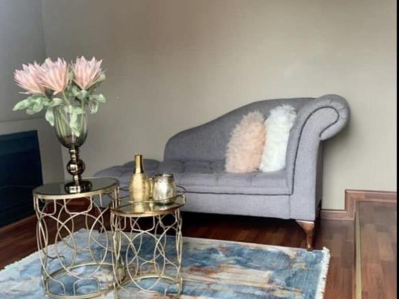 A cozy living room area featuring warm-toned laminate flooring, neutral wall finishes, and a built-in fireplace.
