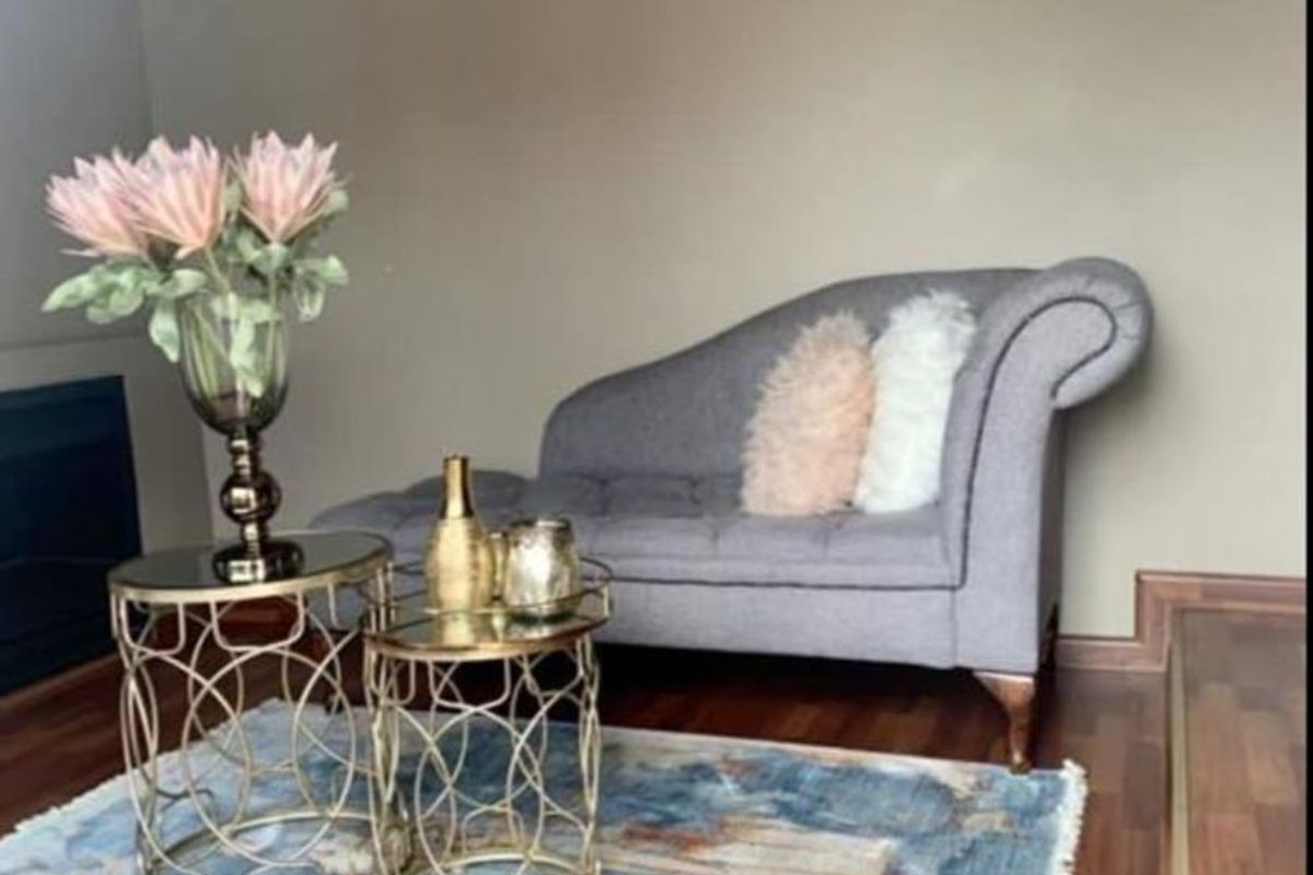 A cozy living room area featuring warm-toned laminate flooring, neutral wall finishes, and a built-in fireplace.