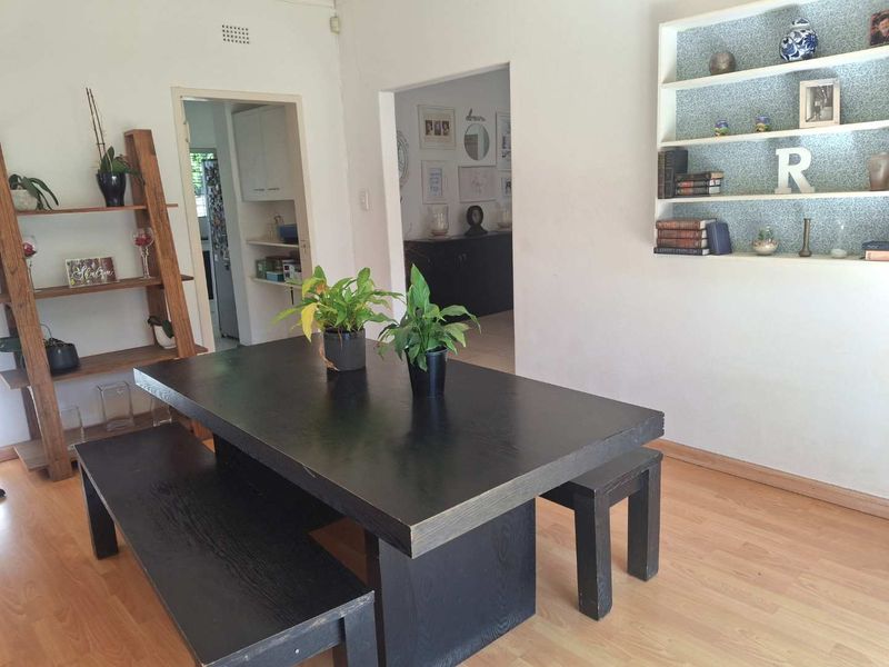 Dining area featuring laminate flooring and a recessed built-in shelving unit, with an open-plan flow leading to adjacent rooms.
