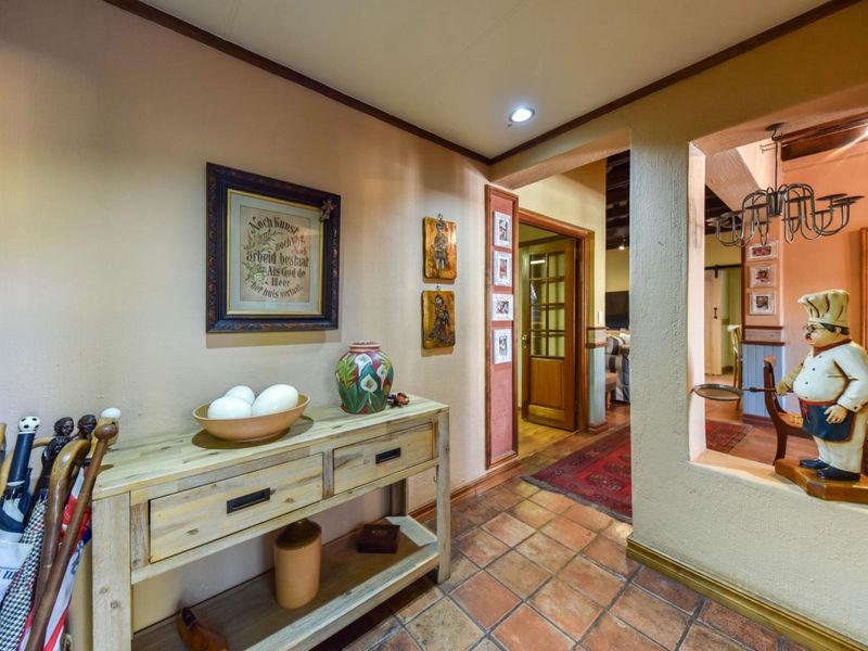 A warm, tiled hallway featuring a pass-through window looking into the dining area, with neutral wall tones and traditional architectural details.