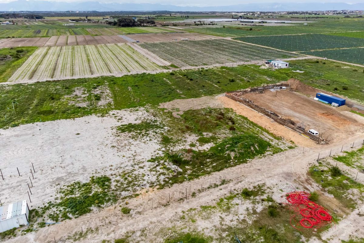 Aerial view of a large agricultural farm plot featuring open land, an excavation area, and surrounding cultivated fields.