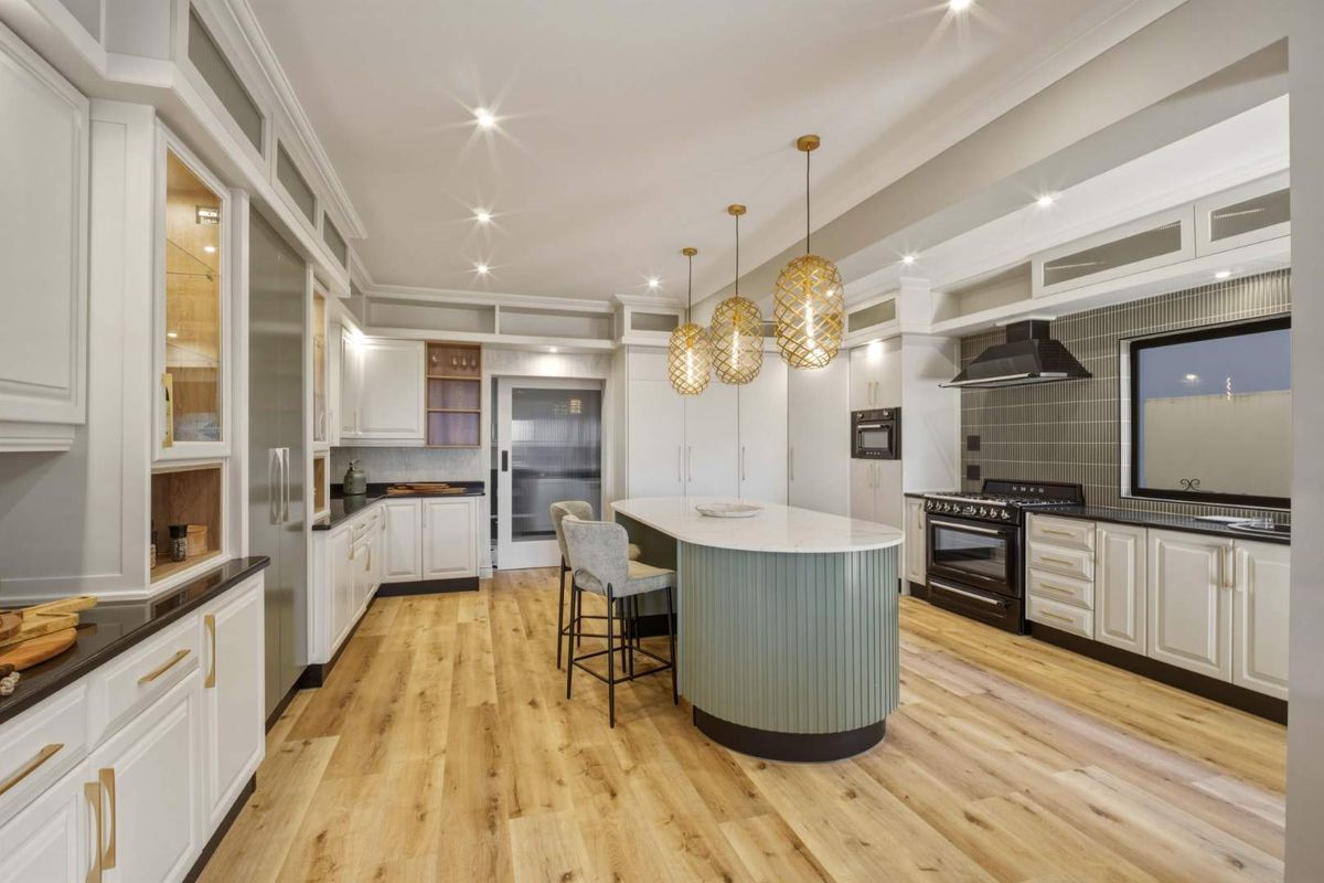 Modern kitchen featuring a central island with fluted detailing, stone countertops, high-end cabinetry, integrated appliances, and stylish pendant lighting.
