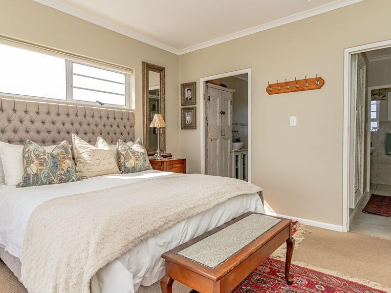 A well-maintained bedroom featuring neutral wall tones, coving, and an adjoining bathroom with tiled flooring.