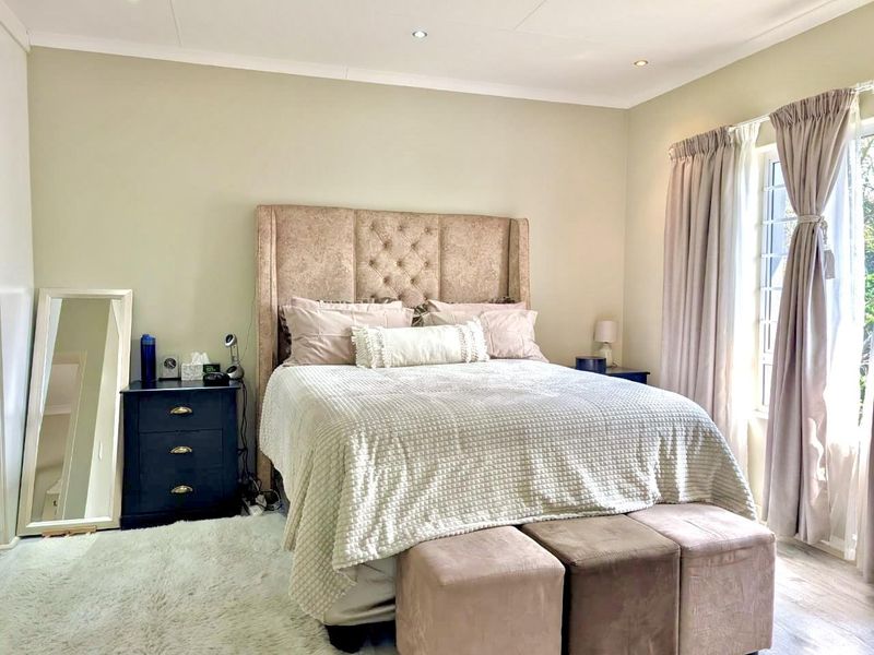 A well-maintained bedroom featuring neutral wall tones, recessed downlighting, and a window with security bars, providing a comfortable and functional living space.