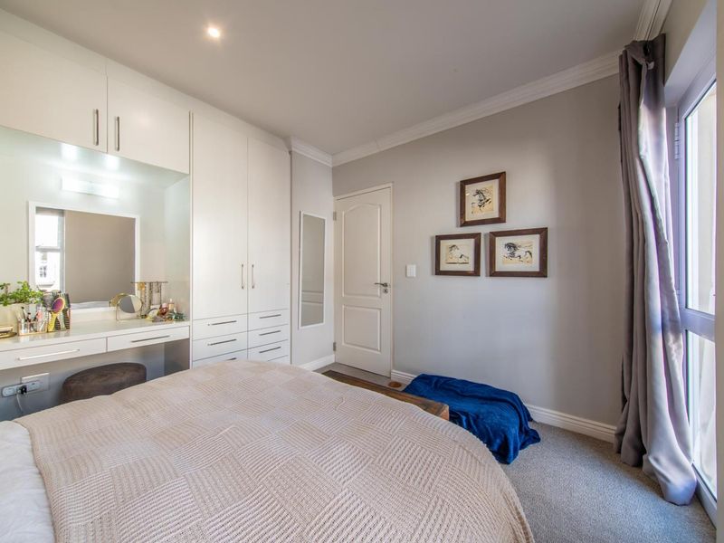 A well-maintained bedroom featuring built-in cabinetry with an integrated vanity, neutral carpeting, and a glass sliding door providing natural light.
