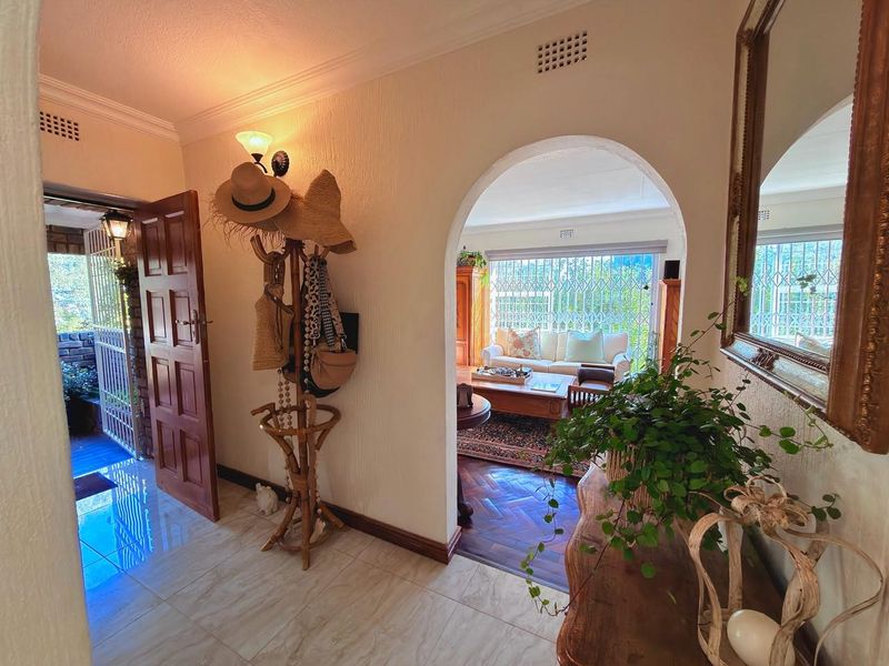 Welcoming entrance hall featuring tiled flooring, a classic arched doorway leading into the living area, and access to the exterior via a timber door.