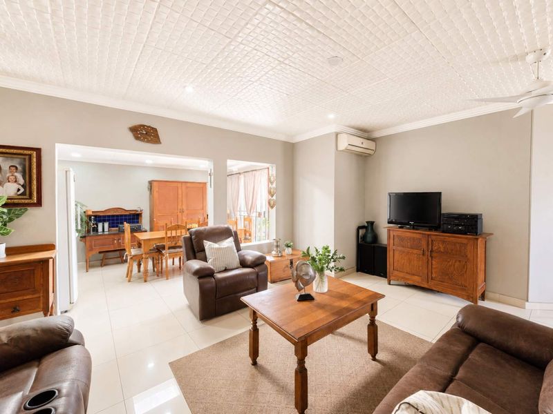 Spacious open-plan living and dining area featuring tiled flooring, a textured ceiling, and a wall-mounted air conditioning unit.