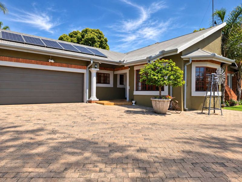 Front elevation of a well-maintained house featuring a paved driveway, integrated garage, and roof-mounted solar panels.