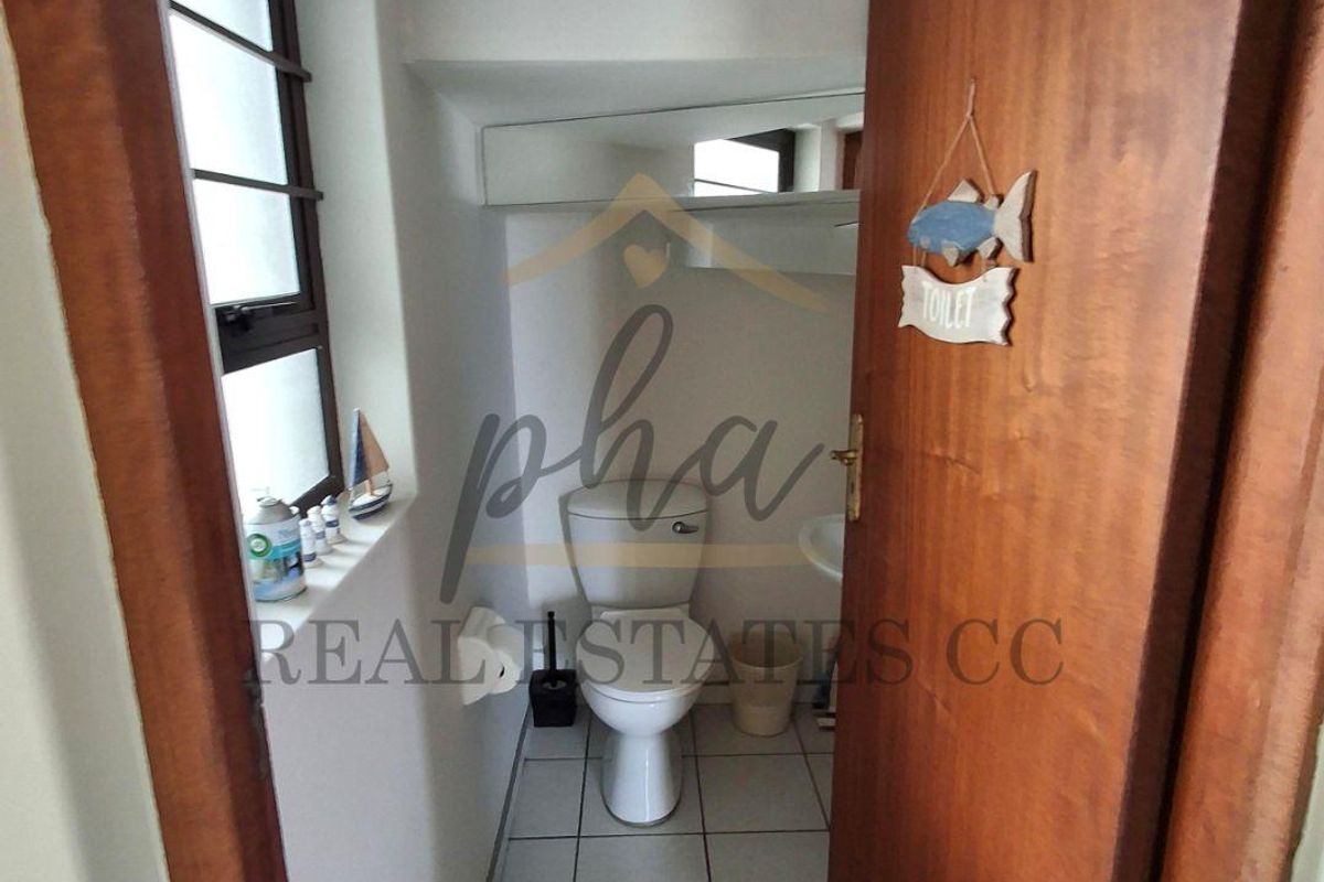 A compact guest bathroom featuring tiled flooring, a standard toilet, and a wall-mounted basin with a mirror.