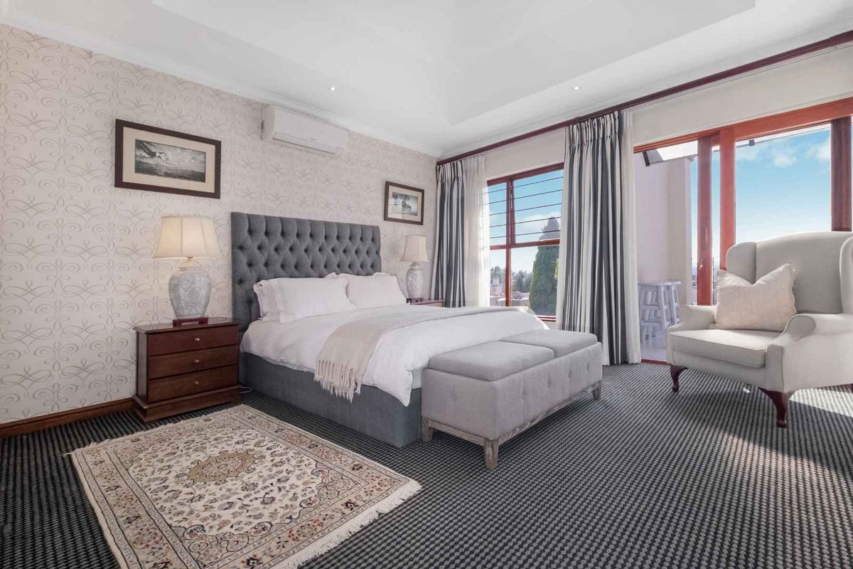 Spacious bedroom featuring a tray ceiling, wall-mounted air conditioning unit, and large sliding glass doors providing access to a private balcony.
