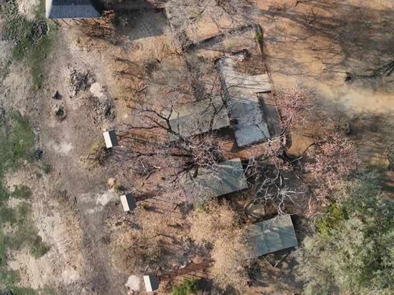 Aerial view of the lodge property, showcasing multiple detached structures, a swimming pool, and natural bushveld surroundings.