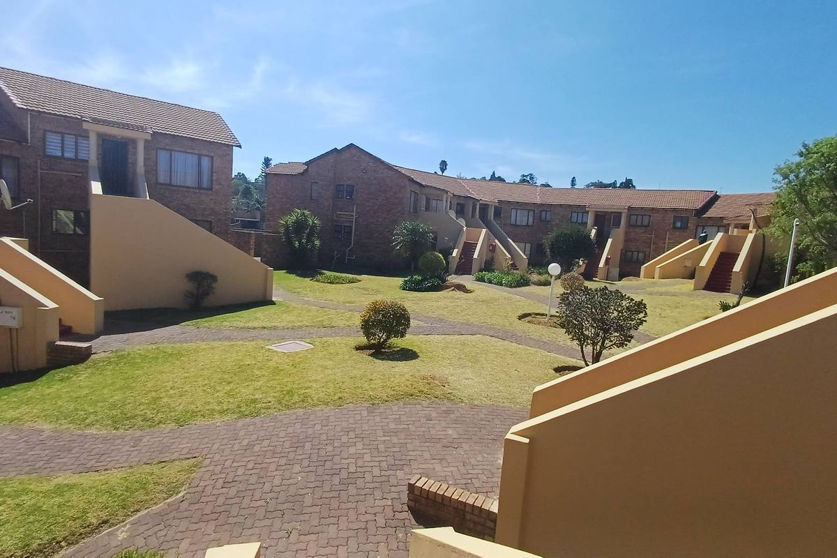 A view of the communal garden area and paved walkways between the brick apartment blocks.
