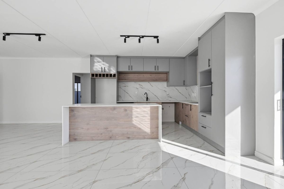 Modern open-plan kitchen featuring sleek grey and wood-tone cabinetry, marble-look tiled flooring, a central island, and contemporary track lighting.