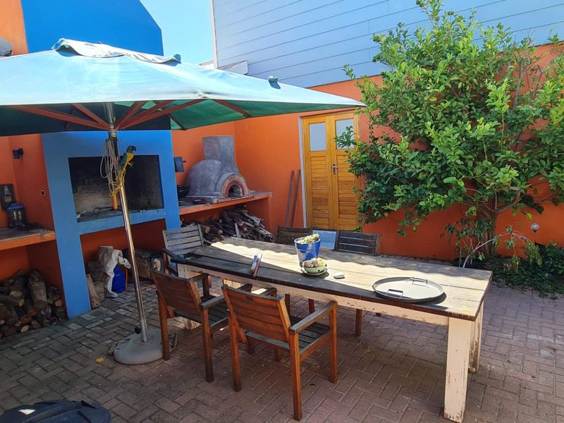 Outdoor patio area featuring a built-in braai, pizza oven, and paved flooring, providing a functional space for outdoor dining and entertainment.