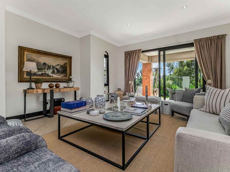 A bright and well-maintained living room featuring tiled flooring, recessed lighting, and large sliding glass doors providing access to the outdoor patio area.