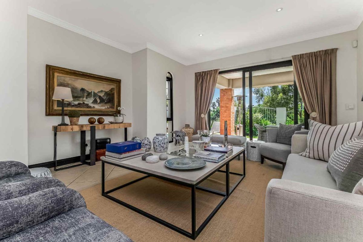 A bright and well-maintained living room featuring tiled flooring, recessed lighting, and large sliding glass doors providing access to the outdoor patio area.