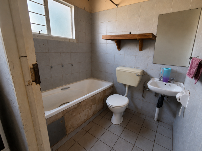 A dated bathroom featuring a bathtub, pedestal sink, and toilet, requiring renovation to update the finishes and fixtures.