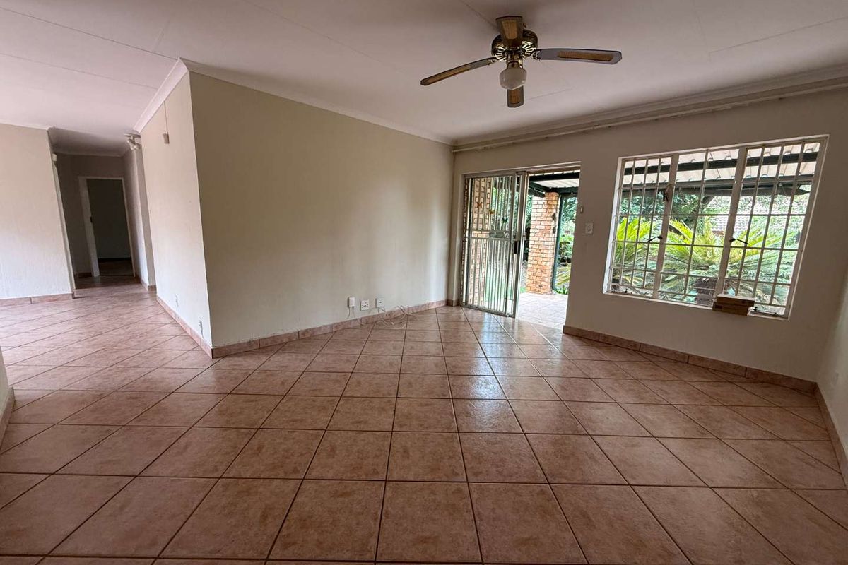 Spacious living area featuring ceramic floor tiles, a ceiling fan, and sliding door access to the outdoor patio.