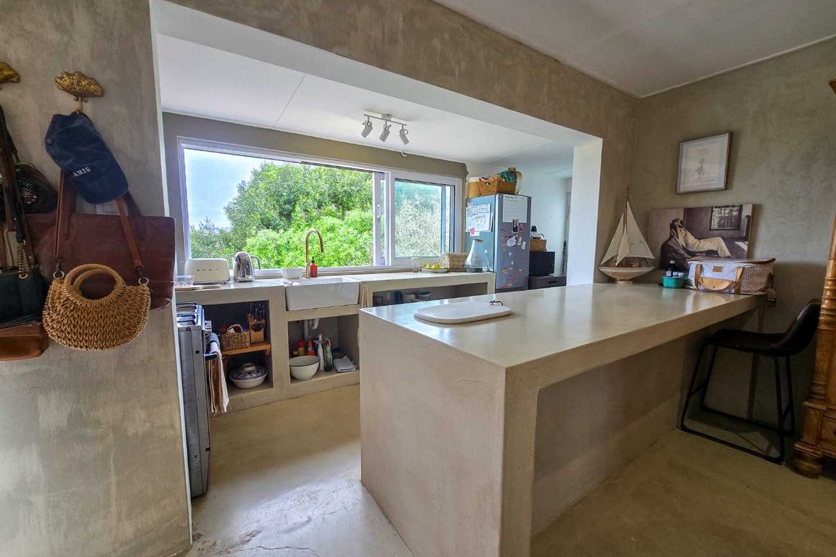 A rustic kitchen featuring custom concrete countertops, a farmhouse-style sink, and an integrated breakfast bar with a minimalist, industrial aesthetic.