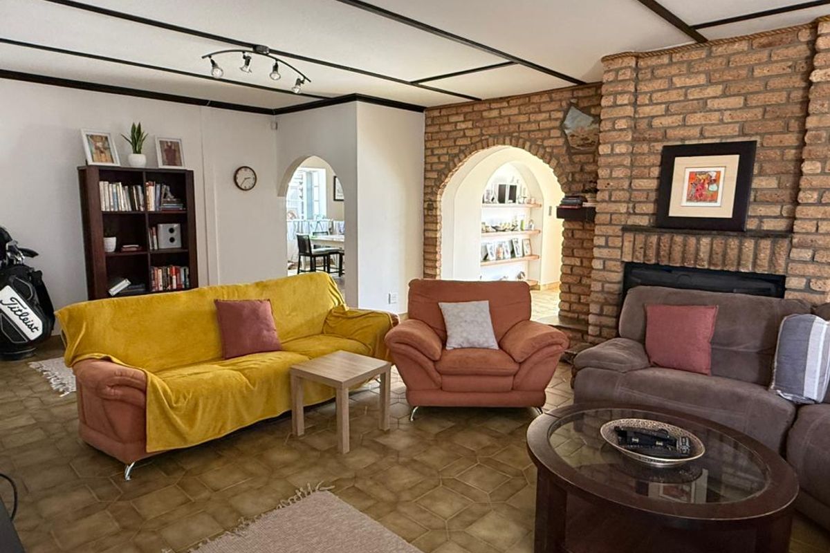 Spacious living room featuring a prominent brick fireplace, exposed beam ceiling, and classic arched doorways leading to adjacent living areas.