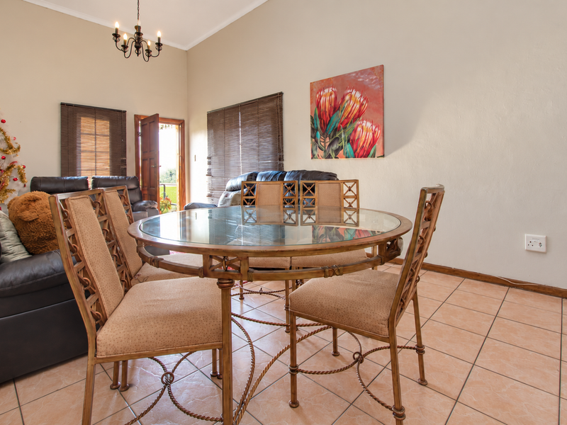 Open plan living and dining area featuring tiled flooring, neutral walls, and natural light through wooden blinds.
