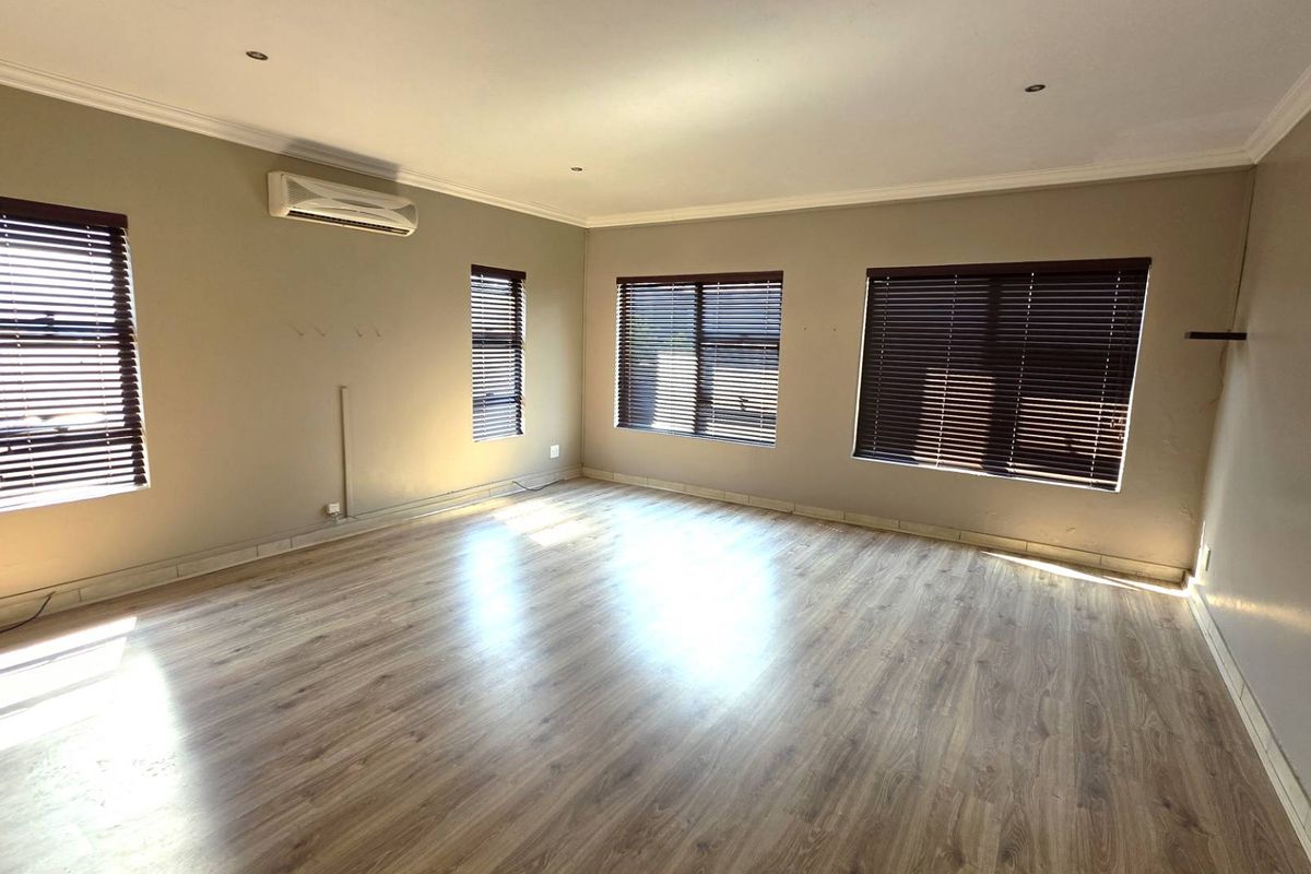 Spacious living room featuring laminate flooring, recessed downlights, venetian blinds, and a wall-mounted split-system air conditioner.