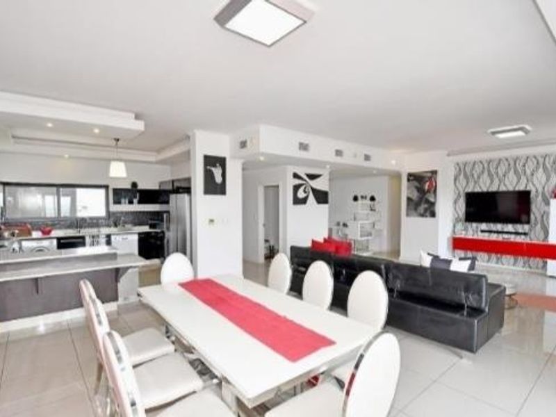Spacious open-plan living area featuring a modern kitchen with island, dining space, and a lounge area with a decorative feature wall.