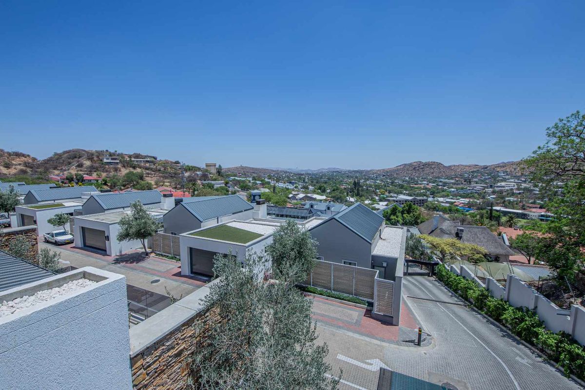 Elevated aerial view of a modern townhouse complex featuring contemporary architecture, paved driveways, and landscaped surroundings with scenic hillside views.