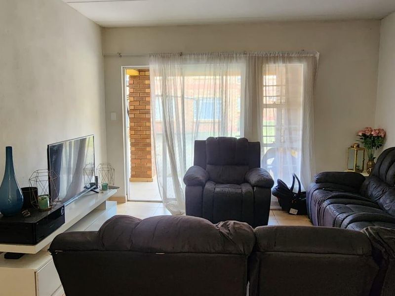 A living room featuring tiled flooring and a sliding glass door providing access to an outdoor area.