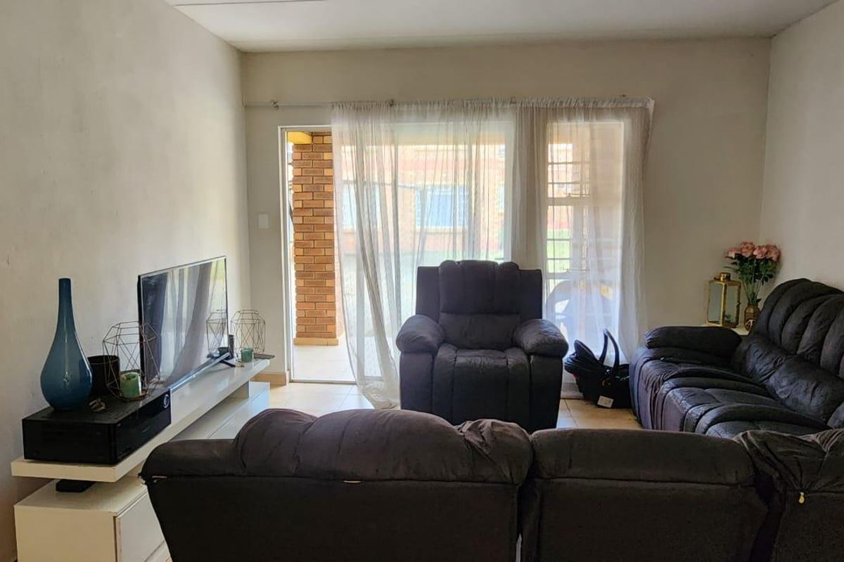 A living room featuring tiled flooring and a sliding glass door providing access to an outdoor area.