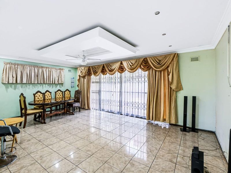 Spacious living area featuring tiled flooring, a recessed ceiling with a fan, and large sliding doors leading to the exterior.
