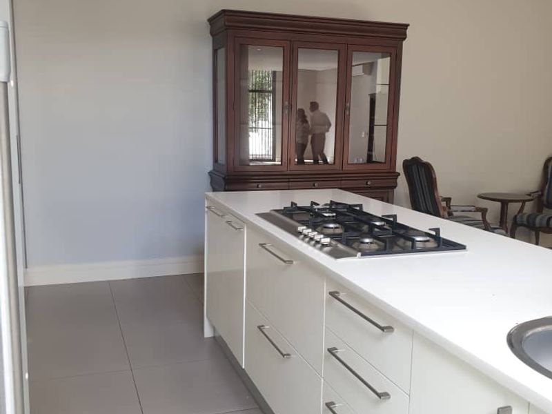 Modern kitchen featuring a central island with a built-in gas hob, sleek white cabinetry, and large format floor tiles.